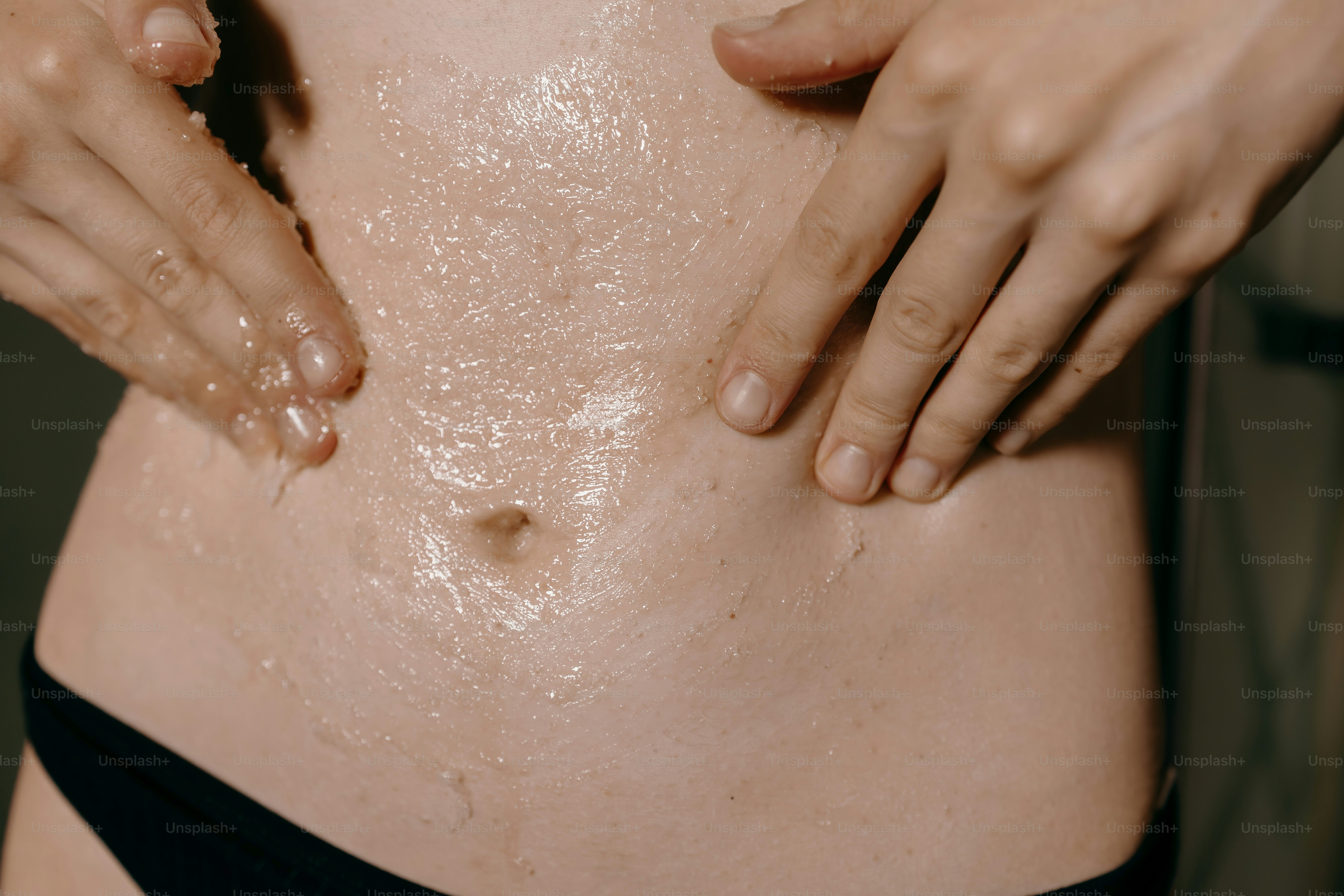 Person applying sugar scrub to stomach